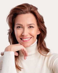 Woman in a white turtleneck resting her chin on her hand
